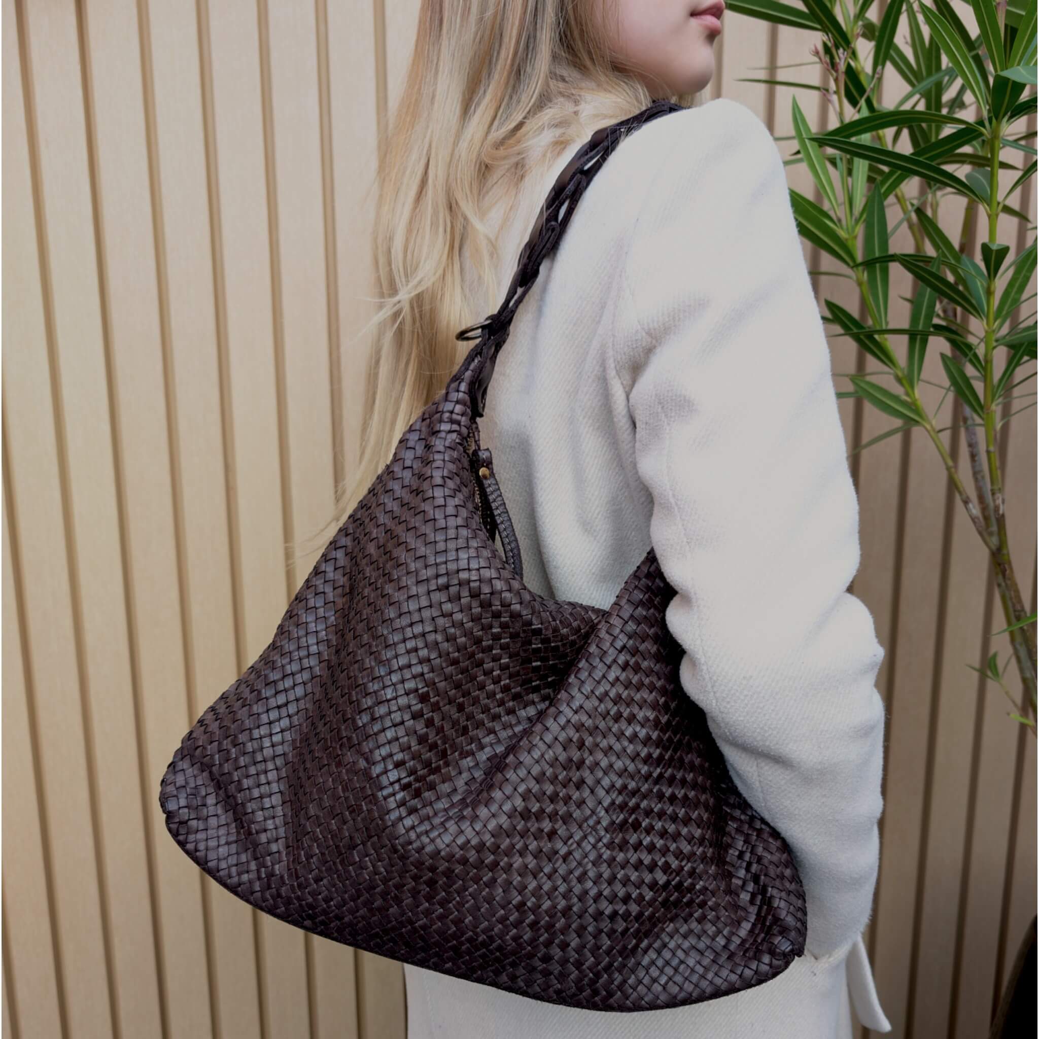 Dark brown woven leather bag on a shoulder of a woman