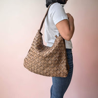 Dark taupe woven leather shoulder bag, carried on the shoulder by our model