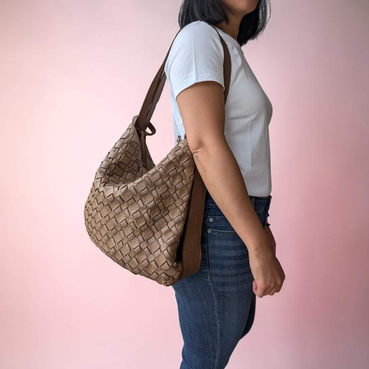 Dark taupe woven leather shoulder bag, carried on the shoulder by our model