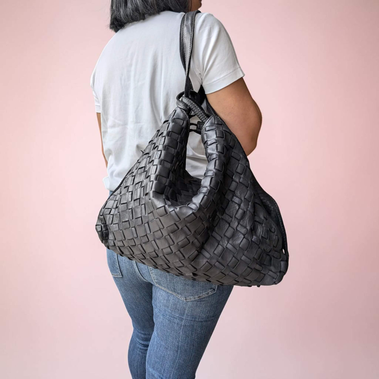 Schultertasche aus geflochtenem Leder in Schwarz, auf einer Schulter als Rucksack getragen