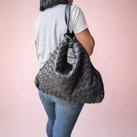Schultertasche aus geflochtenem Leder in Schwarz, auf einer Schulter als Rucksack getragen