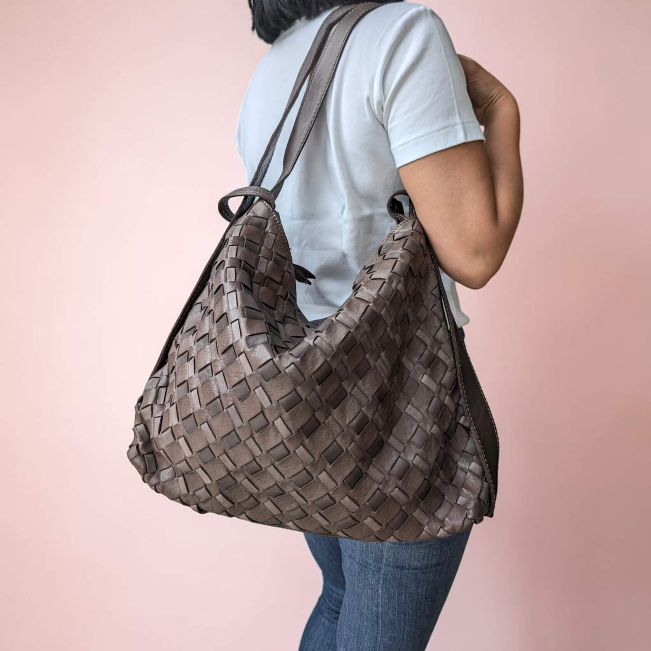 Schultertasche aus geflochtenem Leder in Schokobraun, vom Model über der Schulter getragen, House of Enira Licea