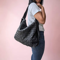 Schultertasche aus geflochtenem Leder in Schwarz, vom Model über der Schulter getragen, House of Enira Licea