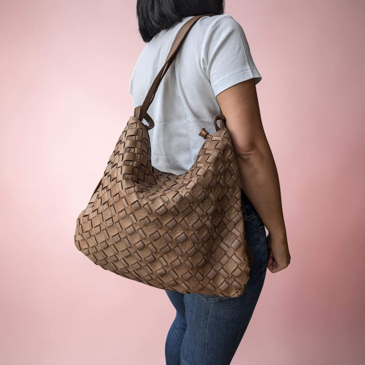 Dark taupe woven leather shoulder bag, carried on the shoulder by our model