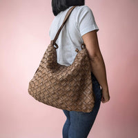 Dark taupe woven leather shoulder bag, carried on the shoulder by our model
