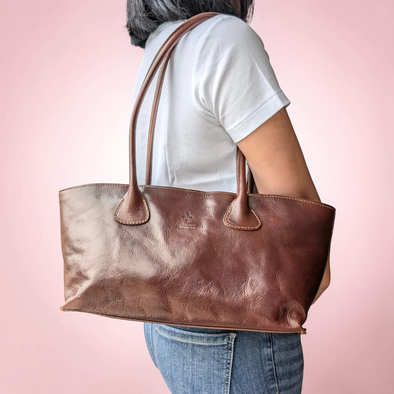 Schultertasche aus Leder in dunklem Kastanienbraun, vom Model über der Schulter getragen