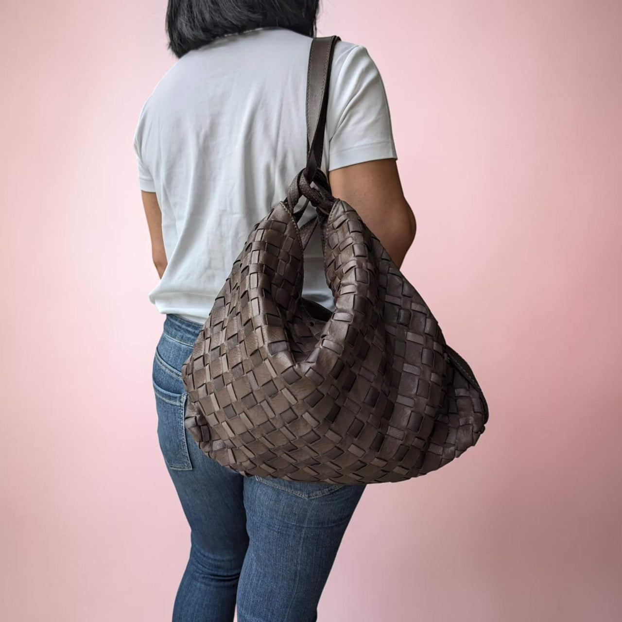 Schultertasche aus geflochtenem Leder in Schokobraun, vom Model als Rucksack getragen