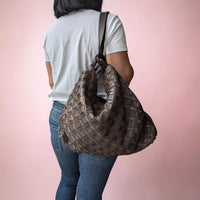 Schultertasche aus geflochtenem Leder in Schokobraun, vom Model als Rucksack getragen