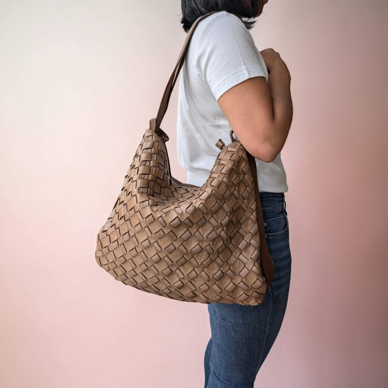 Dark taupe woven leather shoulder bag, carried on the shoulder by our model