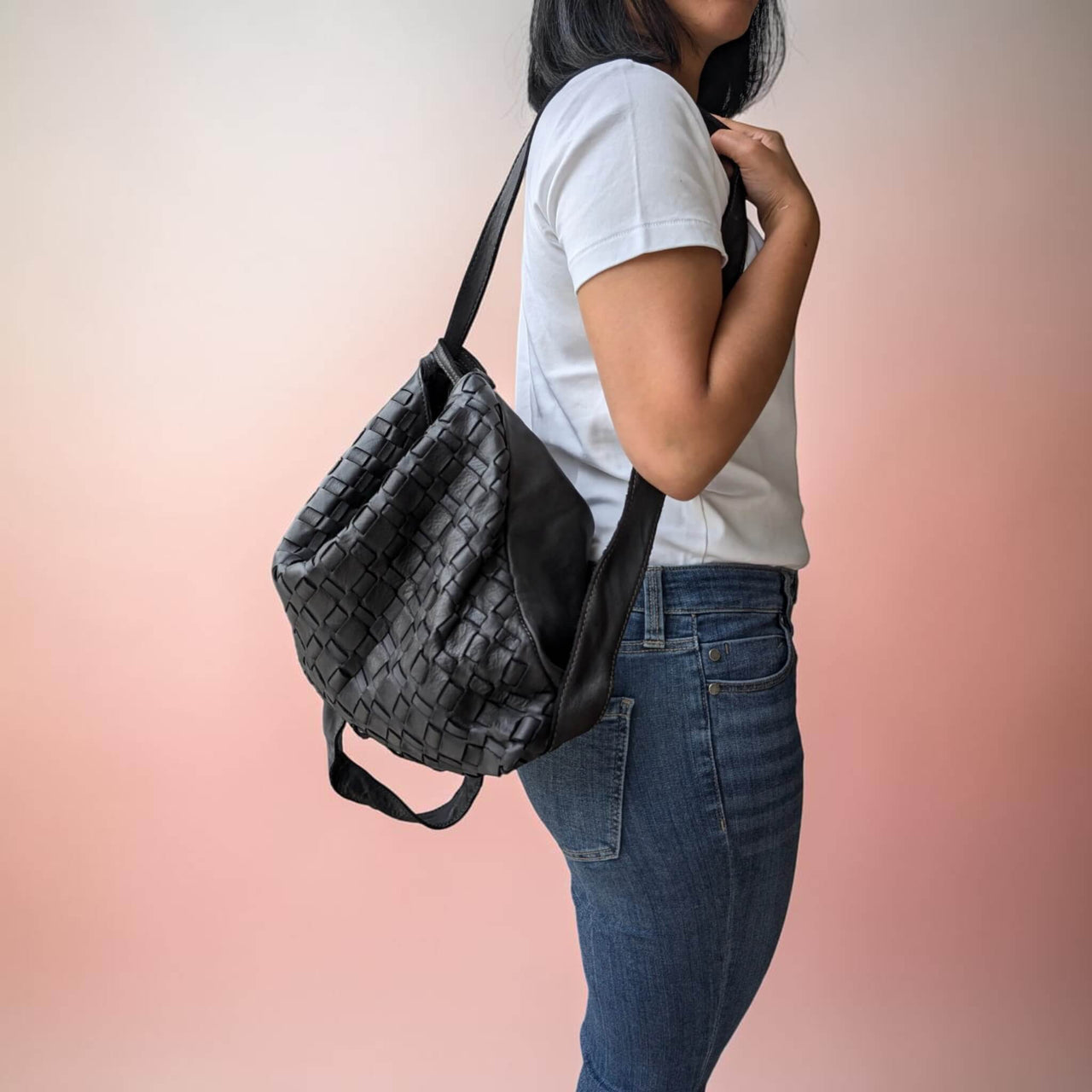 Seitenansicht: Schultertasche aus geflochtenem Leder in Schwarz, auf einer Schulter getragen