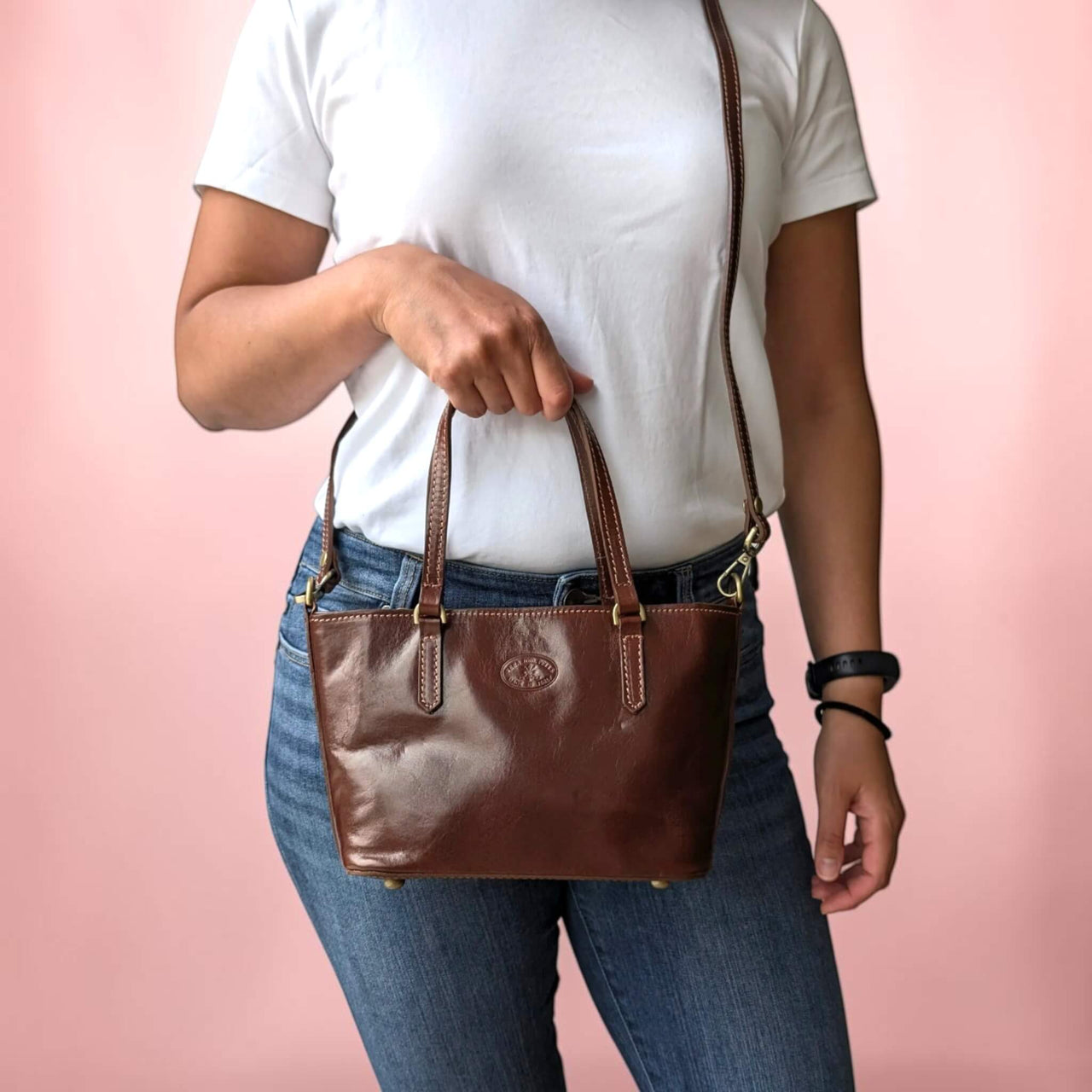 Handtasche aus Leder in dunklem Kastanienbraun, am Tragegriff gehalten