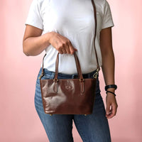 Handtasche aus Leder in dunklem Kastanienbraun, am Tragegriff gehalten