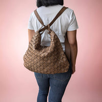 Back view of dark taupe woven leather shoulder bag, worn as a backpack